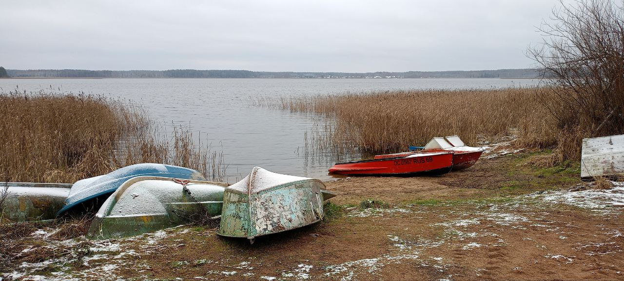 Зимние лодки на берегу, где вода замерла в тишине