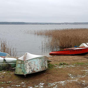 Зимние лодки на берегу, где вода замерла в тишине